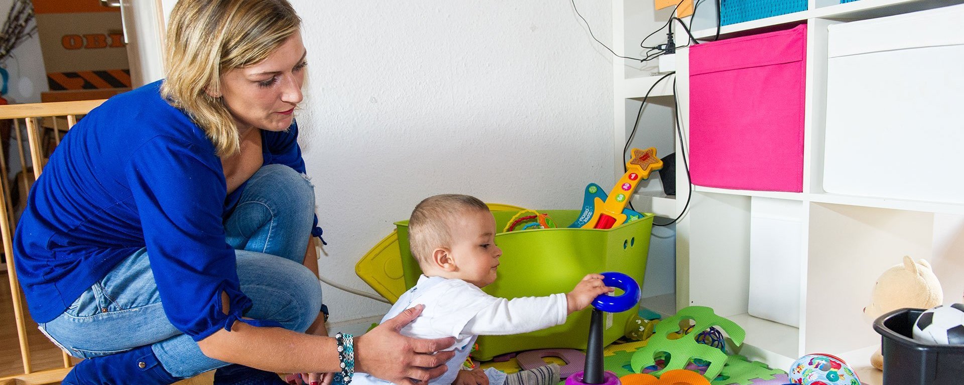 Eine Mutter spielt mit ihrem kleinen Kind mit bunten Spielzeugen.