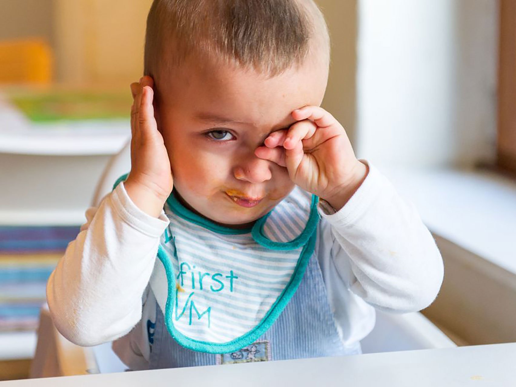 Kind reibt sich nach dem Essen müde die Augen.